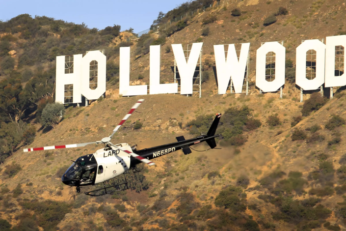 Image of a police helicopter flying next to the Hollywood sign.
