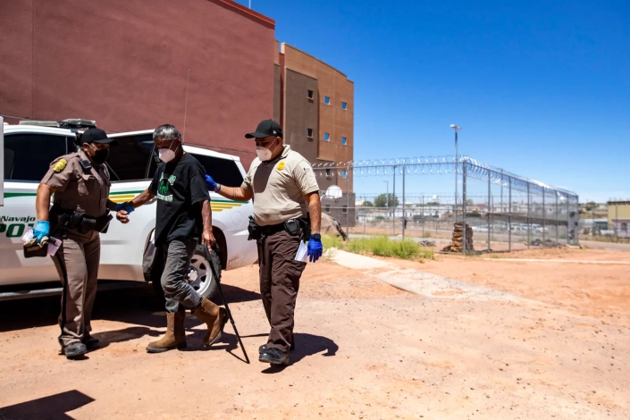 A police officer and corrections officer take a person into custody at a jail facility on the Navajo Reservation in Arizona.